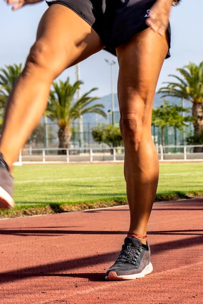 Foto piernas de una corredora entrenando en la pista del estadio