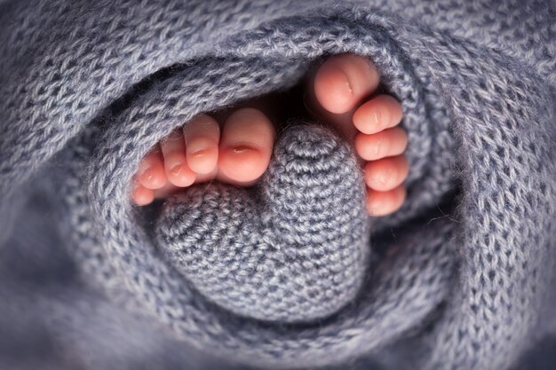 Piernas y dedos de los pies de un recién nacido en una suave manta gris con un corazón