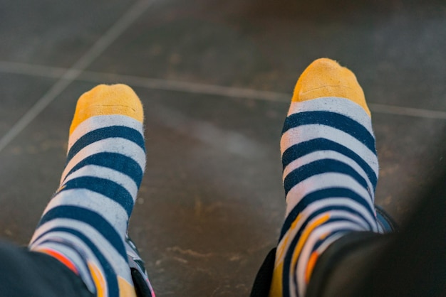 Las piernas de dos hombres se destacan en calcetines a rayas. Vista desde la cara. Cómic. Divertido. Multicolor. Raro