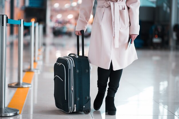 Piernas de empresaria con equipaje en el aeropuerto.