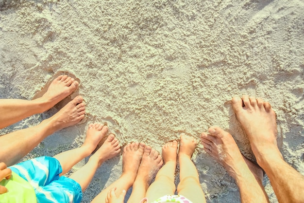 piernas de la familia en la arena junto al mar