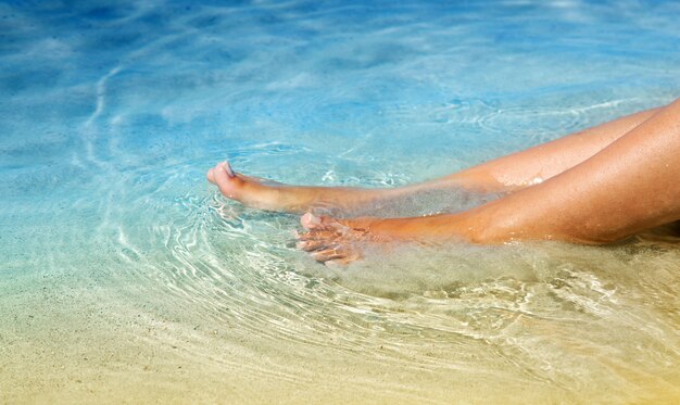 Piernas femeninas en el agua cristalina.