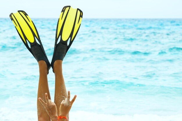 Foto piernas femeninas en aletas en la persona de la playa