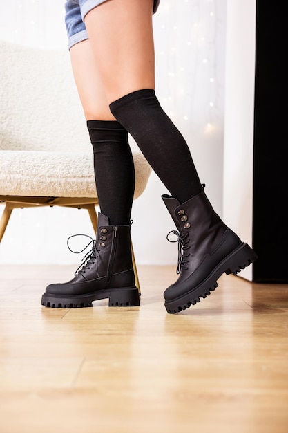 Piernas femeninas con botas de cuero negro. Nueva colección de botas de invierno para mujer
