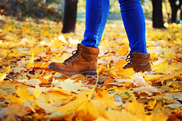 Piernas femeninas con botas en hojas de otoño