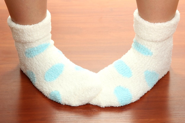 Piernas femeninas en calcetines con lunares en piso laminado