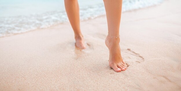 Piernas femeninas caminando por la playa descalzo primer plano de las perfectas piernas bronceadas de una niña