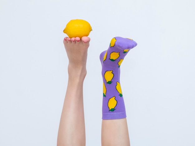 Foto piernas femeninas en coloridos calcetines con limones aislado sobre fondo blanco.