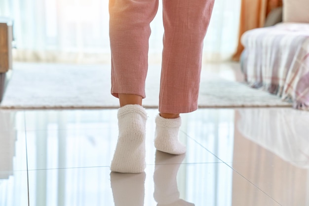 Piernas femeninas en cómodos y cómodos calcetines de punto suave en un cálido piso calentado en la sala de estar en casa