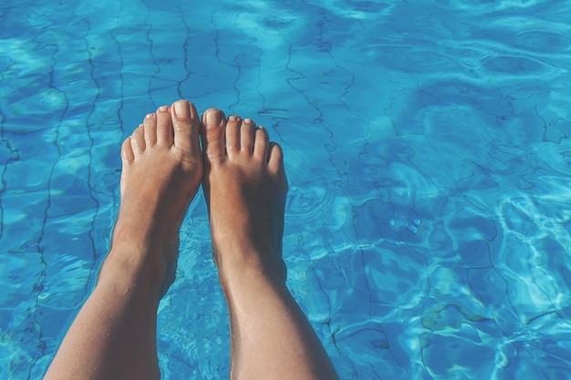 Foto piernas femeninas desnudas sobre un fondo de agua azul
