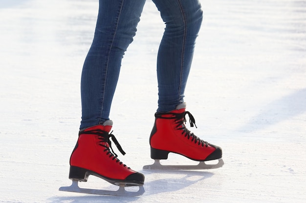 Piernas femeninas en patines sobre una pista de hielo