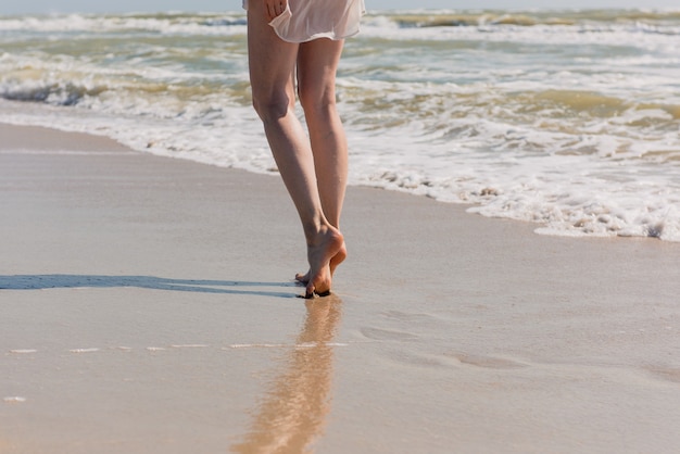 Piernas femeninas en la playa. Cerca del cuerpo de la mujer en el mar y la arena