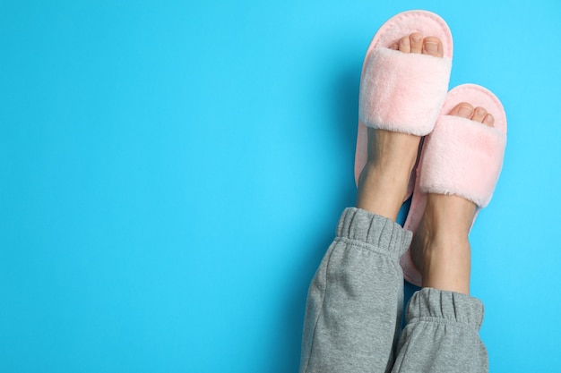 Piernas femeninas en zapatillas rosa sobre fondo azul.