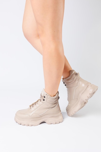 Piernas femeninas en zapatos de cuero beige de la nueva colección sobre un fondo blanco piernas femeninas en zapatos de moda hechos de cuero ecológico primavera 2022