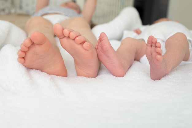 Piernas hermanas primer plano. primer plano de pie de bebé. las hermanas estan en la cama