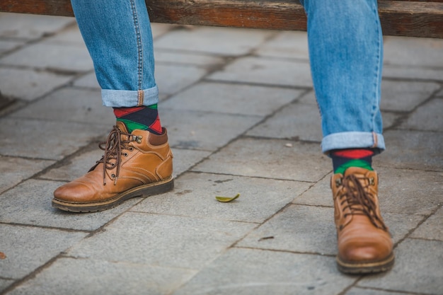 Piernas de hombre con botas y calcetines rojos verdes de cerca