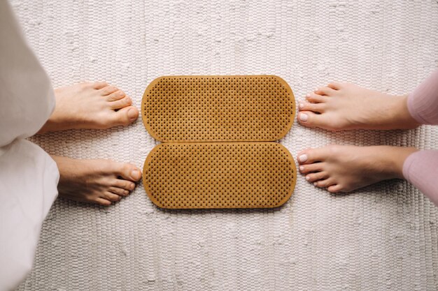 Las piernas de un hombre y una mujer se paran junto a tablas con clavos para clases de Yoga