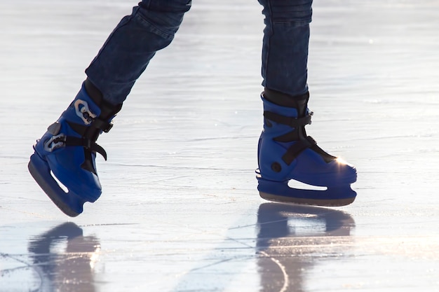 Piernas de un hombre patinando sobre una pista de hielo. Pasatiempos y deportes. Vacaciones y actividades invernales.