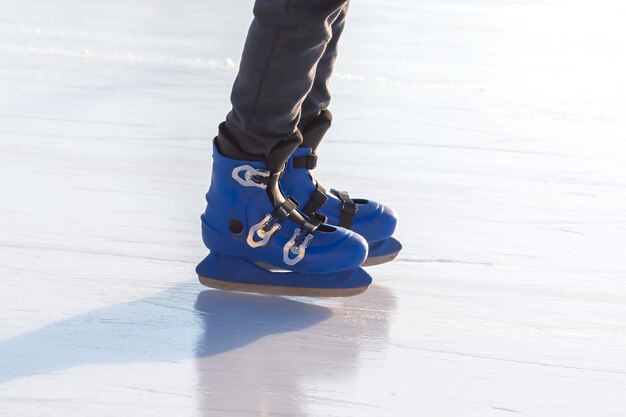 Las piernas de un hombre en patines azules cabalga sobre una pista de hielo. aficiones y ocio. Deportes de invierno