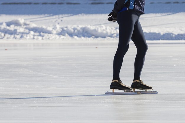 Las piernas del hombre sobre patines anillo de hielo - deporte de invierno en un día soleado, telefoto de cerca