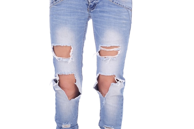 Piernas humanas en los jeans rasgados sobre fondo blanco.