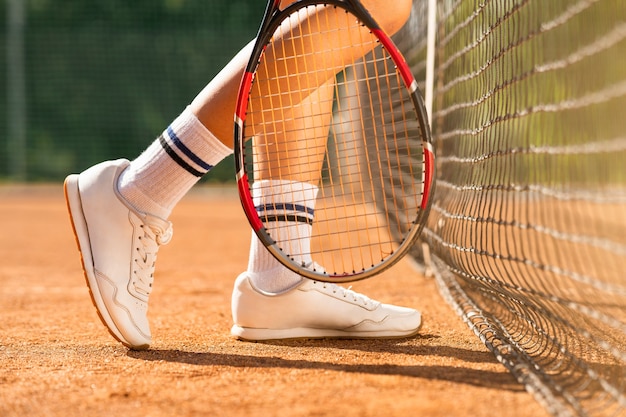 Piernas de jugador de tenis femenino cerca de la red