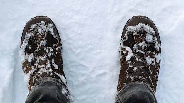 Piernas masculinas en botas de invierno cubiertas de nieve, vista superior. Paseo de invierno en la nieve. Concéntrate en tus piernas. Hermoso clima de invierno blanco con nevadas frescas.