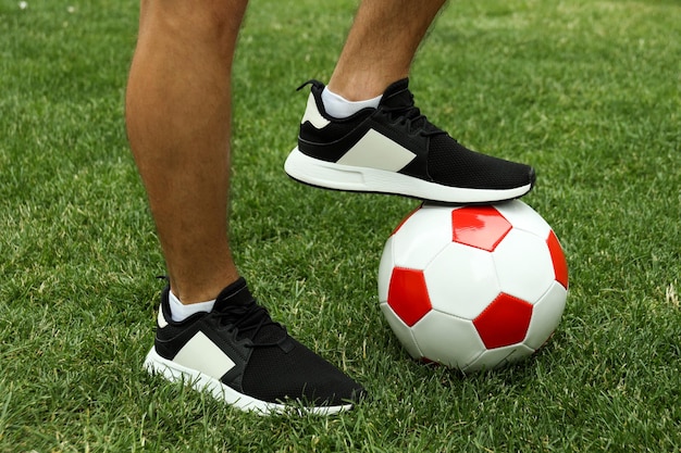 Piernas masculinas en zapatillas y pelota de fútbol sobre hierba