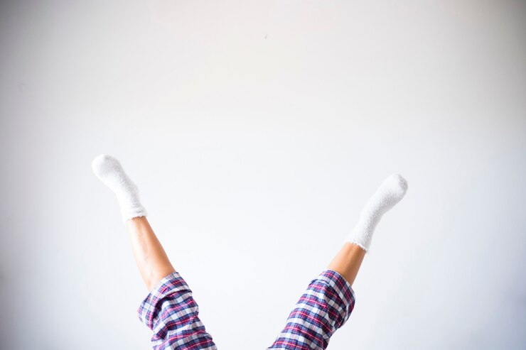 Foto piernas de mujer hacia abajo hacia arriba en posición inversa con fondo de pared de sala blanca - concepto de ejercicios de fitness en casa y gente de estilo de vida saludable y divertido - copyspace y su texto aquí