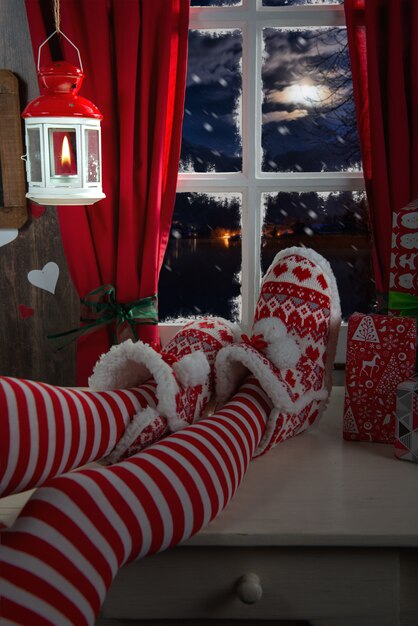 Piernas de mujer con calcetines en la mesa y el fondo de la ventana, concepto de Navidad