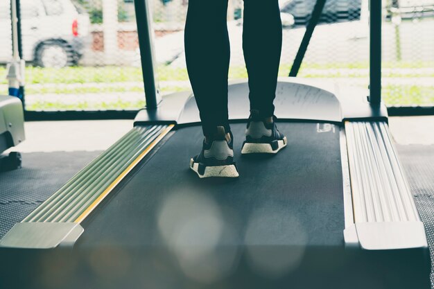 Piernas de la mujer en la caminadora o la máquina de seguimiento en el gimnasio