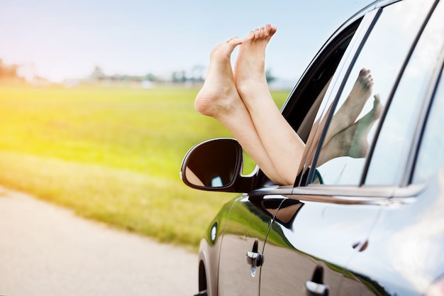 Piernas de la mujer fuera de la ventana del coche.