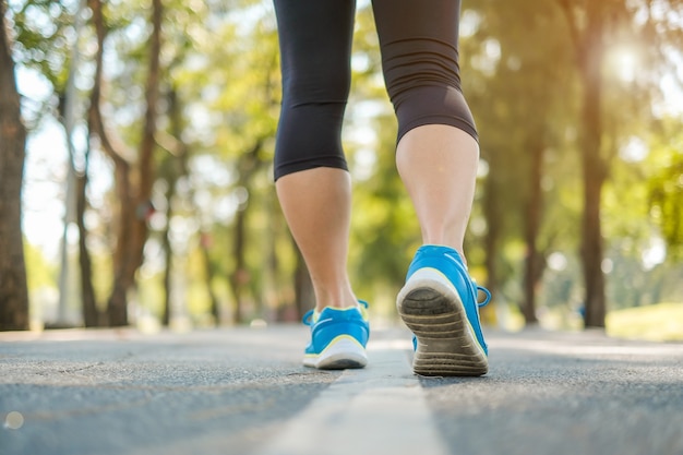 piernas de la mujer joven de la aptitud caminando y corriendo en el parque al aire libre