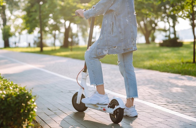 Piernas de una mujer montando un scooter eléctrico Concepto de transporte ecológico