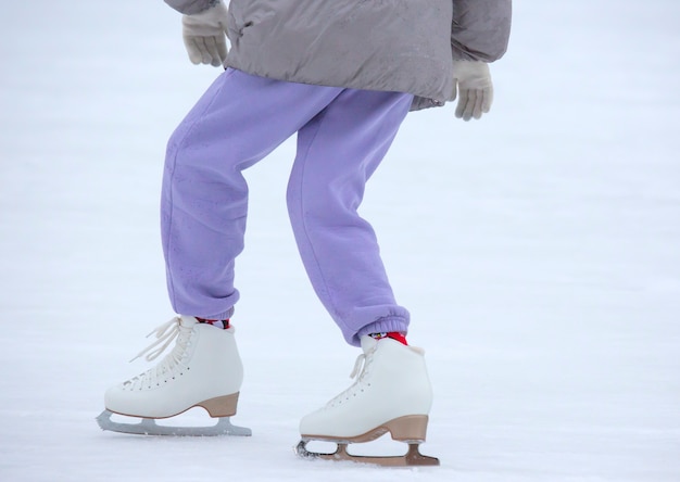 Piernas de una mujer patinando sobre hielo en una pista de hielo. aficiones y ocio