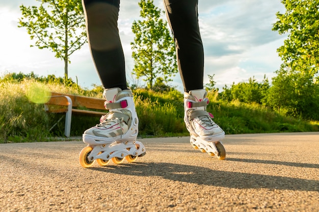 Piernas de mujer con patines en línea en día soleado. Tiro del primer de los patines en línea blancos en el camino.