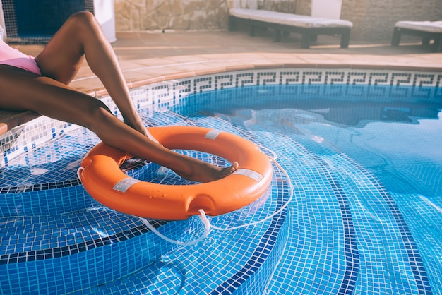 Piernas de mujer en una piscina con salvavidas