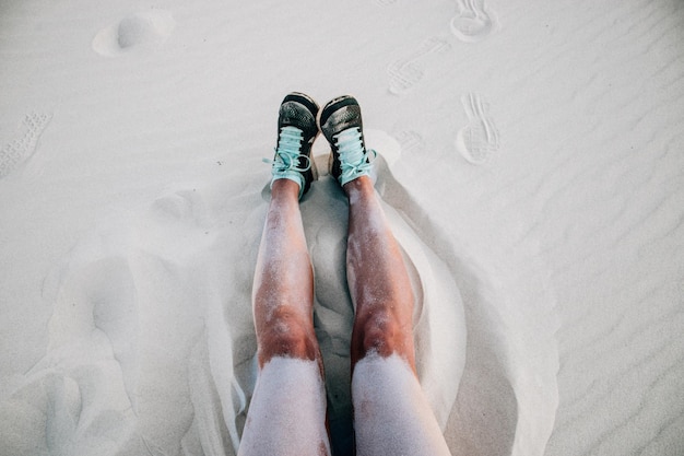 Foto las piernas de una mujer sentada en la arena