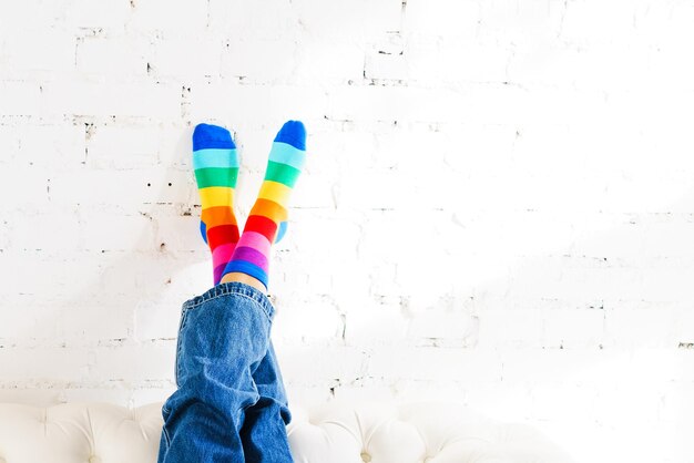 Foto las piernas de las mujeres en calcetines arco iris contra un concepto de fondo de pared de ladrillo blanco