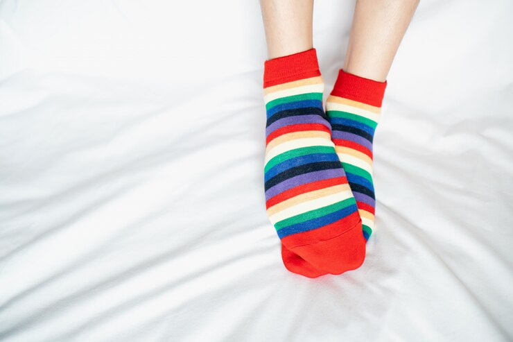 Foto piernas de las mujeres en calcetines de colores alternativos, soporte lateral en el piso de tela blanca.