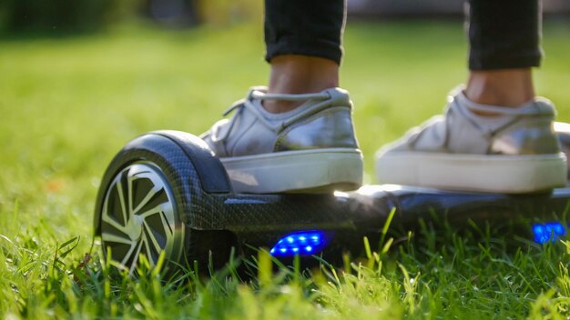 Piernas de mujeres en zapatillas de deporte en un giroscopio en el parque en medio de la hierba, el giroscopio brilla