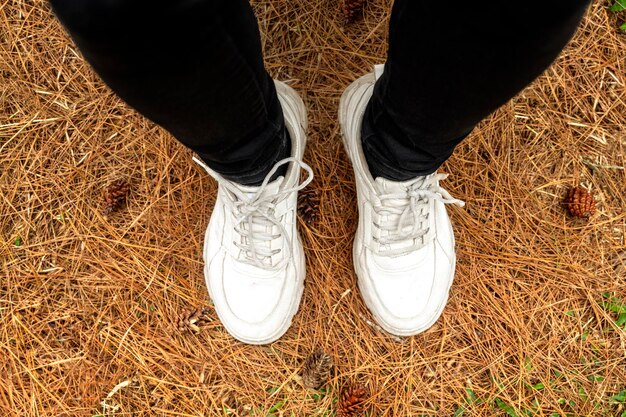 Las piernas de las mujeres con zapatos blancos caminando en el bosque