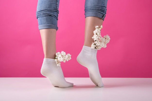 Piernas de niña en calcetines en los que se insertan flores lilas concepto y piernas salud femenina Foto Premium