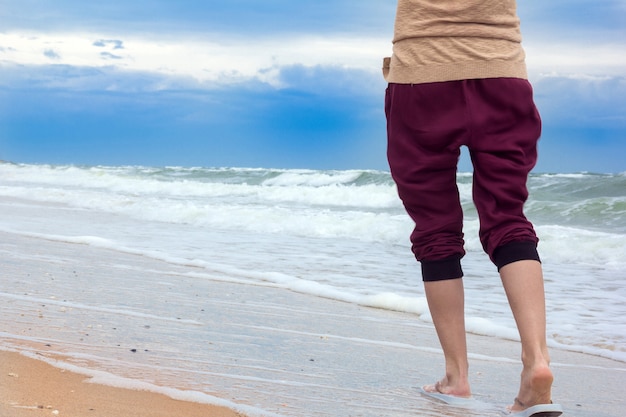 Las piernas de la niña caminando por la playa.