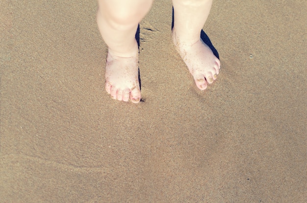 Piernas de niños parados en la playa