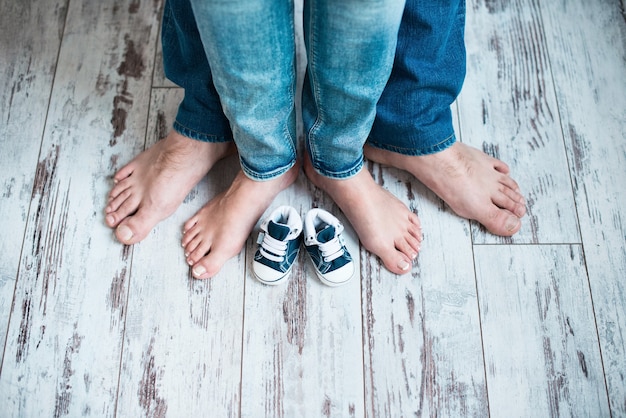 Foto piernas de padres con zapatillas para niños esperando al bebé