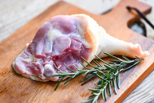 Piernas de pato crudas con especias de hierbas listas para cocinar en una tabla de cortar de madera Carne de pato fresca para alimentos