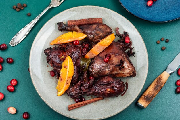 Foto piernas de pollo picantes a la parrilla horneadas con especias de naranja y bayas rojas