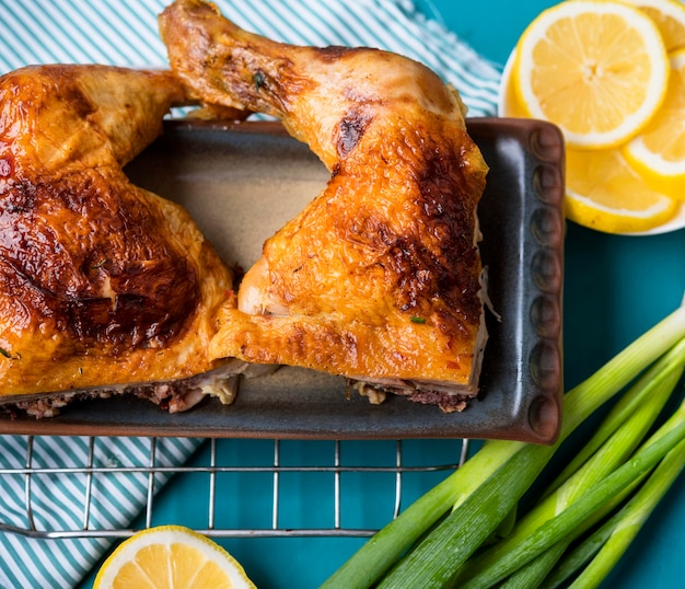 Foto piernas de pollo de primer plano con rodajas de limón y cebolla verde