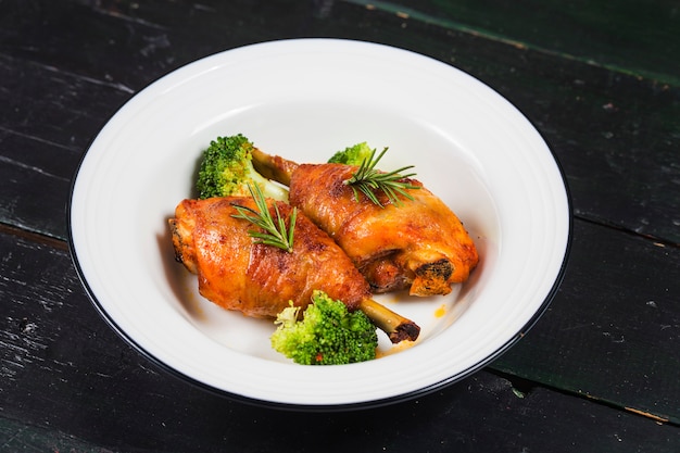 Piernas de pollo con las verduras en la tabla de madera.